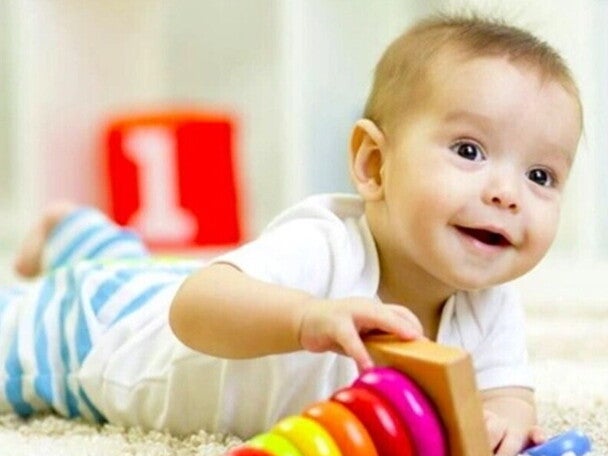 תינוק שוכב על הבטן ולצידו משחק השחלת טבעות