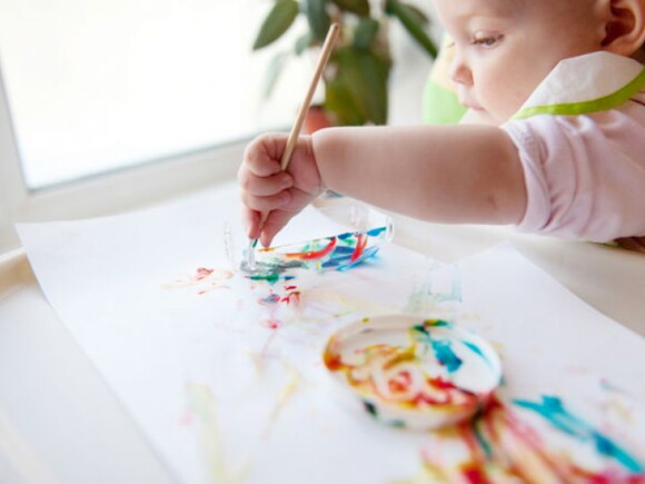 ילד כבן שנה מצייר עם מכחול על דף