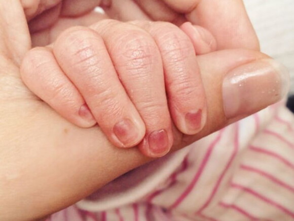 יד של תינוק שרק נולדת אוחזת היד אמו