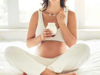 אישה בתחילת הריון אוכלת יוגורט
