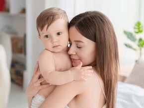 אמא צעירה מחבקת באהבה תינוק כבן חצי שנה