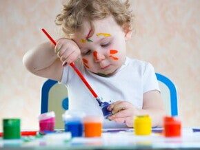 פעוט כבן שנה מחזיק מכחול ומצייר על דף