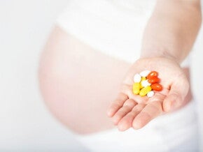 הריונית מחזיקה בידה תוספי תזונה