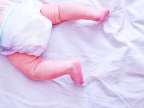 תינוק שוכב על בטנו ולגופו חיתול