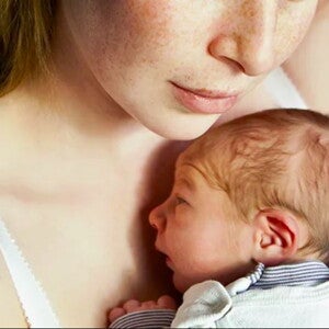 אמא מחזיקה תינוק קטן על חזה