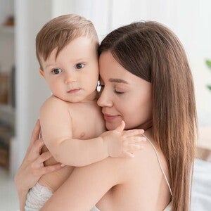 אמא צעירה מחבקת באהבה תינוק כבן חצי שנה