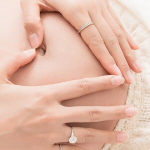 אישה הרה מניחה את ידיה על בטנה בצורת לב