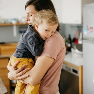אמא מחזיקה את תינוקה על הידיים כשהם במטבח