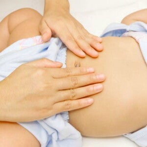 ידי אמא מעסות בטן של תינוק קטן