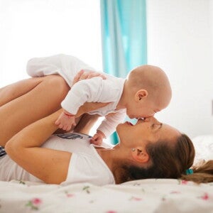 אמא ותינוק משתעשעים יחד במיטה