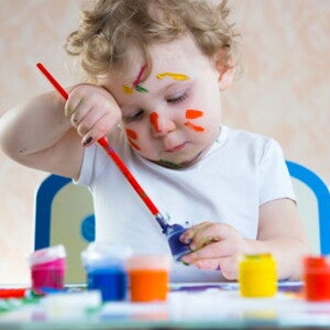 פעוט כבן שנה מחזיק מכחול ומצייר על דף