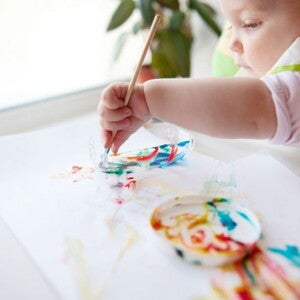 ילד כבן שנה מצייר עם מכחול על דף