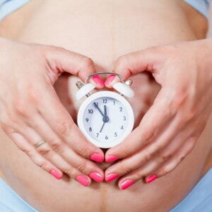 הריונית עם שעון על ביטנה