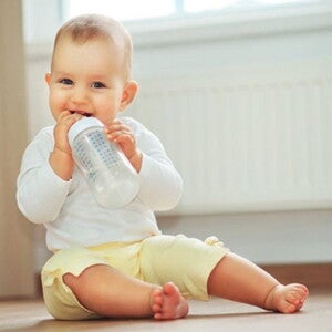 פעוט יושב ושותה מבקבוק