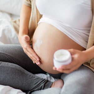 הריונית מורחת קרם על ביטנה