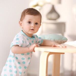 תינוק עומד לצד כיסא