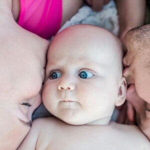 תינוק שוכב במרכז בין שני הוריו