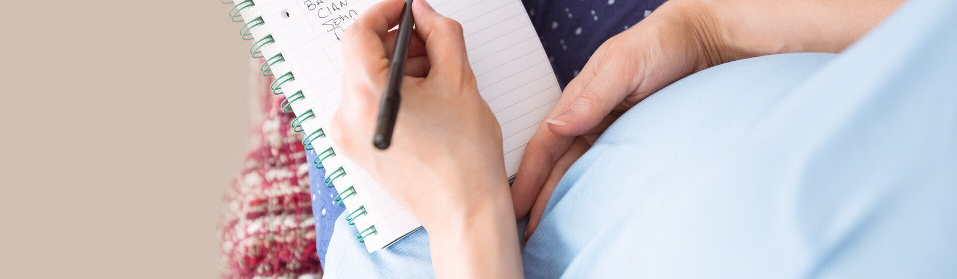 אמא מניחה יד על בטנה וכותבת במחברת