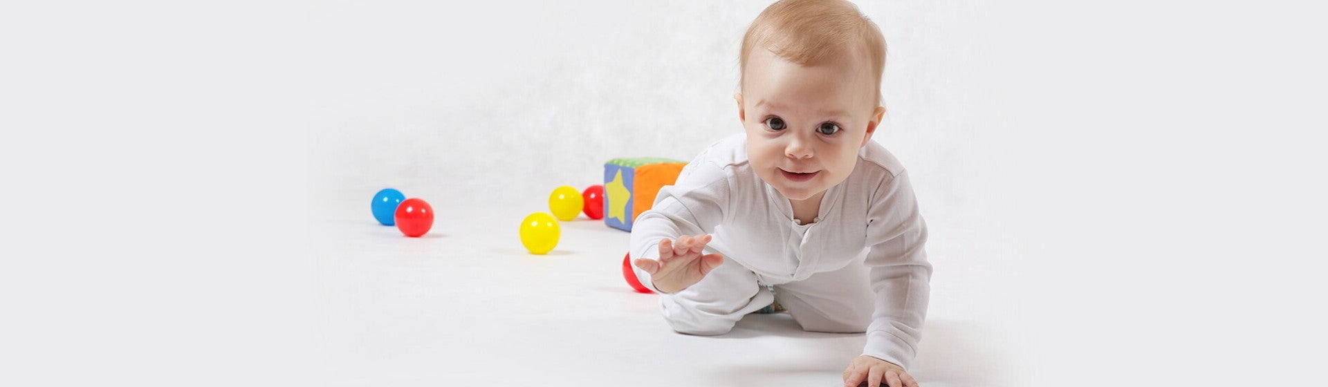 תינוק זוחל לעבר המצלמה כשמאחוריו צעצועי התפתחות