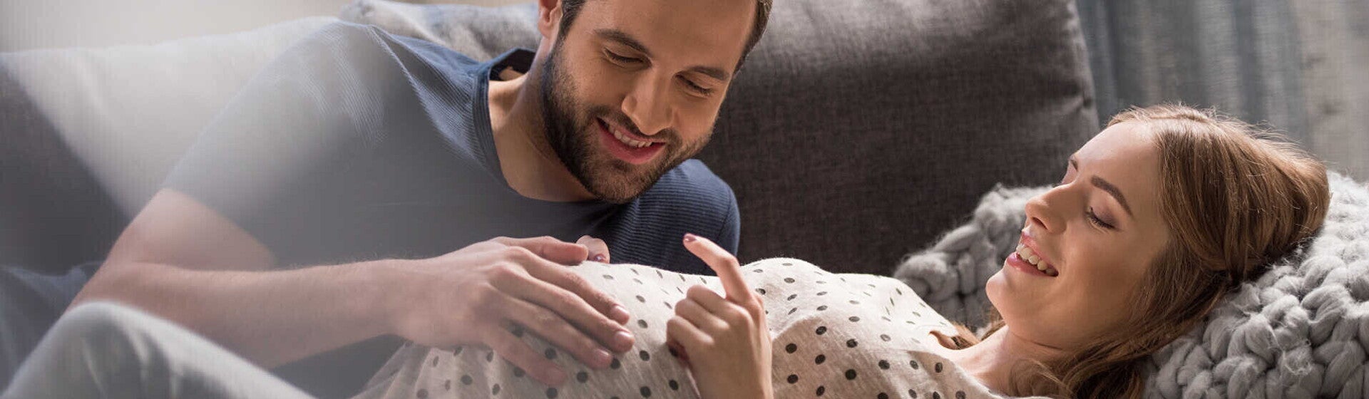 גבר מניח את ידו על בטנה של זוגתו ההרה, שניהם שמחים