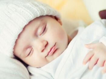 תינוקת ישנה ברוגע עם כובע לראשה