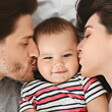 שני הורים, אחד מכל צד, מנשקים תינוק כבן חצי שנה